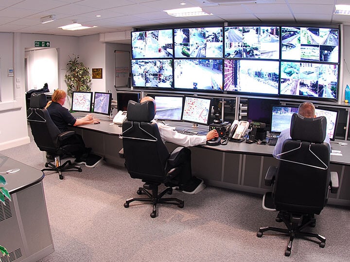 security workers sitting at a desk monitoring security cameras for a business