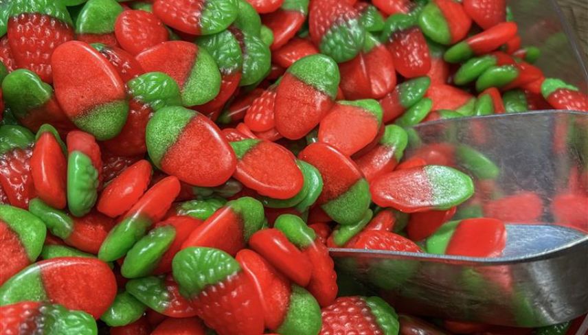 A bowl filled with an assortment of red and green candies, showcasing vibrant colors and various shapes.